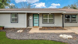 A single-story house with a light gray exterior, a blue front door, and a number "608" on the door. - Cozy 6 bed - 3 bath home close to Main Street (Fredericksburg)