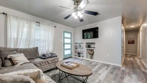 A living room with a sofa, coffee table, and ceiling fan. - Cozy 6 bed - 3 bath home close to Main Street (Fredericksburg)