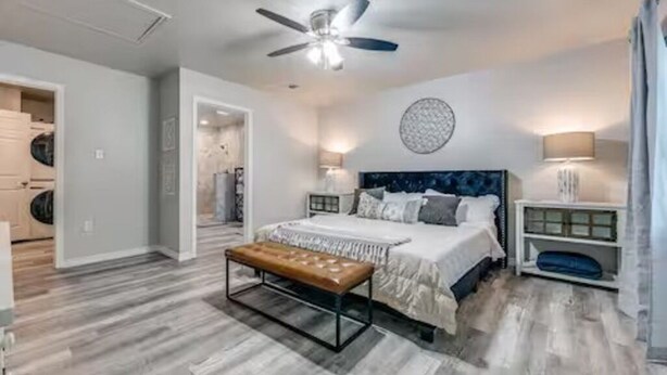 A bedroom with a bed, a bench, a ceiling fan, and a wall with a circular design. - Cozy 6 bed - 3 bath home close to Main Street (Fredericksburg)