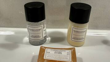 Two bottles of Gilchrist & Soames shampoo and a bar of glycerin soap on a bathroom counter.