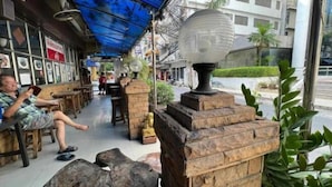 An outdoor cafe with tables and chairs, a blue awning, and a decorative lamp. - Collection O Thaiphiphat House Silom (Bangkok)
