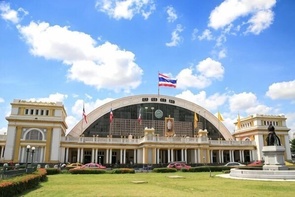 Un edificio grande e histórico con una cúpula central, varias banderas y una estatua en primer plano.