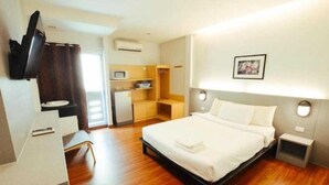 A hotel room with a bed, a desk, a TV, a microwave, and a small kitchenette. - Collection O Thaiphiphat House Silom (Bangkok)