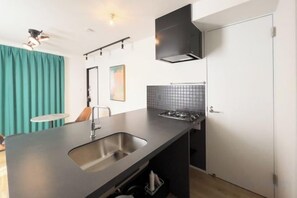 A modern kitchen with a built-in sink, black cabinets, and a tiled backsplash. - trias540 (Tokyo)