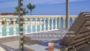 A balcony with a pool, lounge chairs, and a drink on the table.