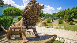 A lion statue in a landscaped garden with a pathway and greenery.
