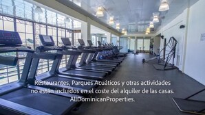 A gym with treadmills and exercise equipment, large windows, and a ceiling with hanging lights.