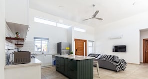 Una cocina amplia con armarios blancos, una isla central y un ventilador de techo.