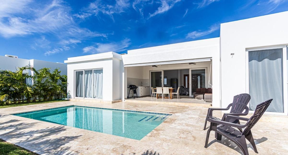 A modern house with a swimming pool, outdoor seating, and a patio area.