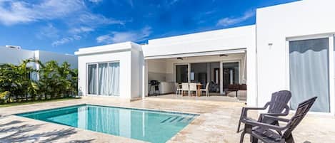 A modern house with a swimming pool, outdoor seating, and a patio area.