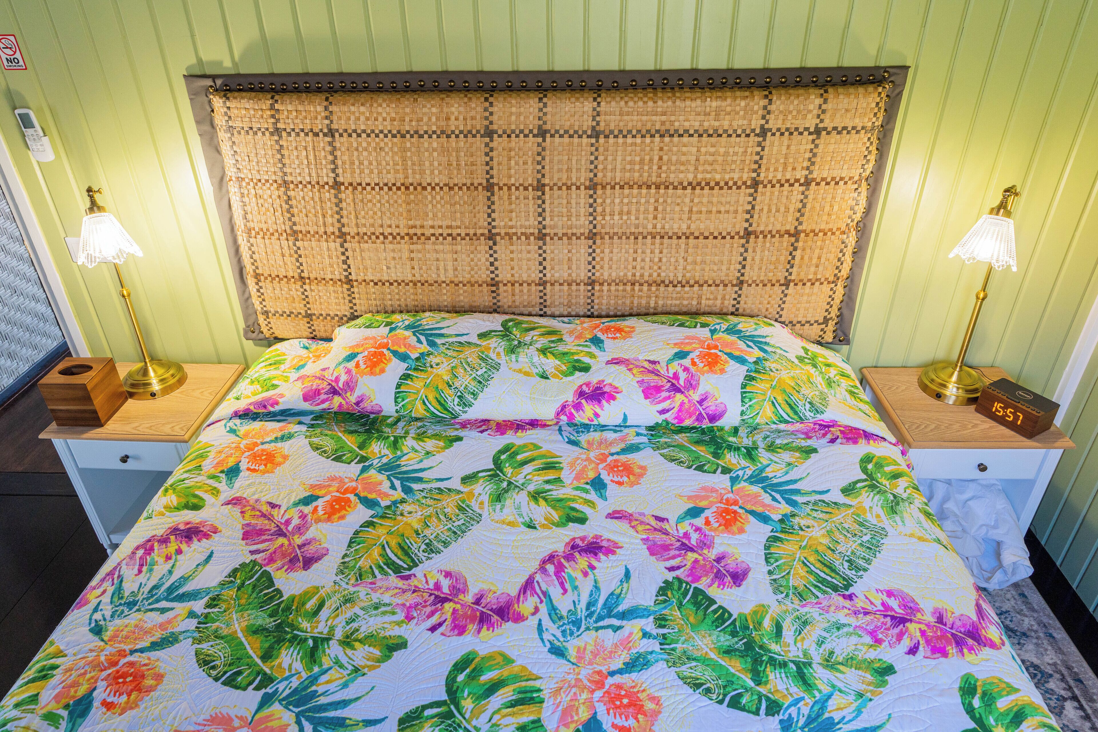 A bed with a floral bedspread, two bedside lamps, and a clock on the nightstand.