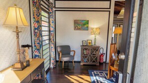 A room with a wooden desk, a chair, a lamp, a bookshelf, and a patterned rug.