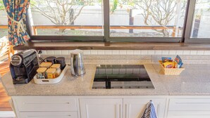 A kitchen with a coffee maker, a kettle, and a basket of snacks.