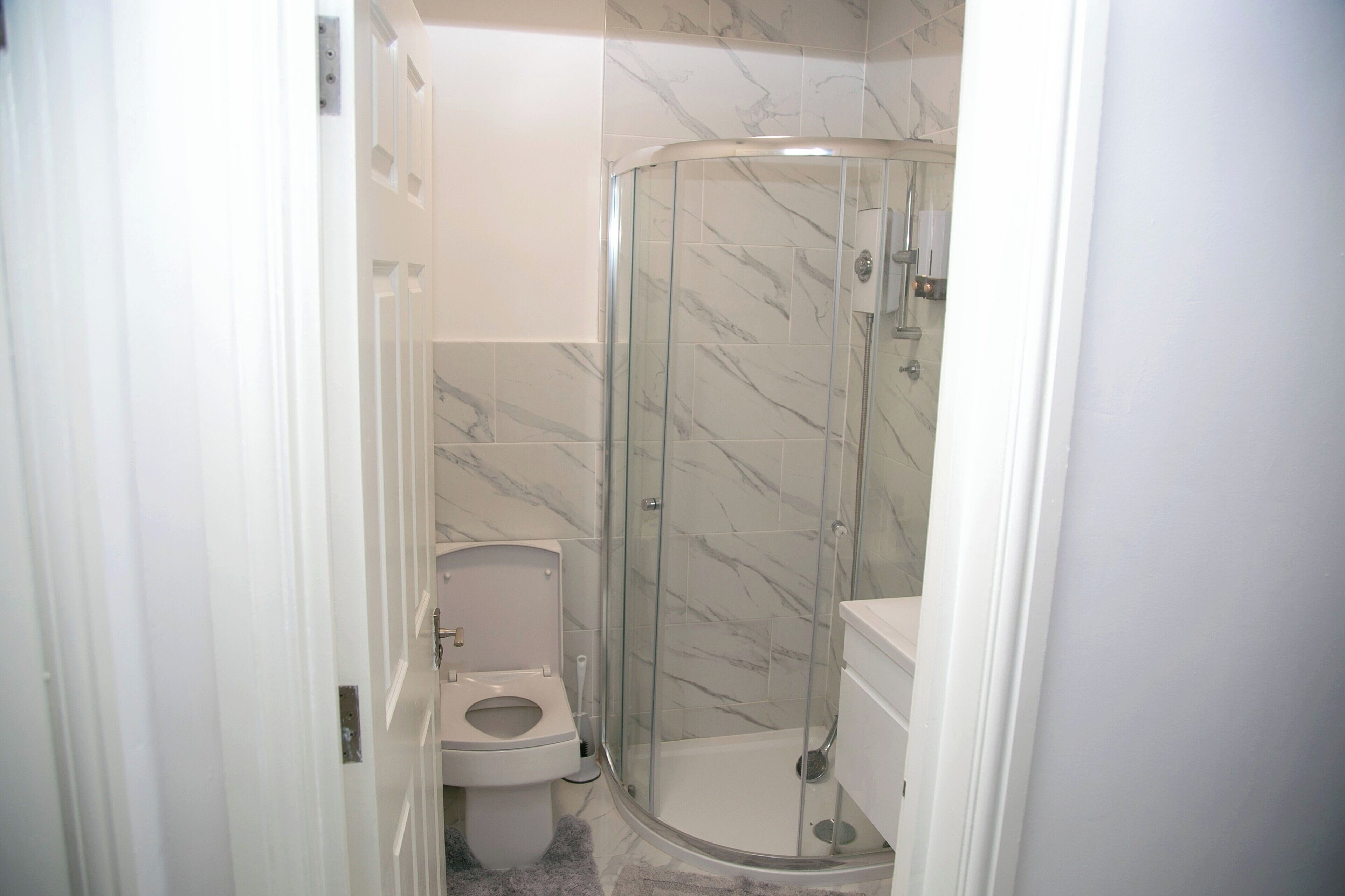 Une salle de bain avec une douche à parois de verre, des toilettes et un lavabo.