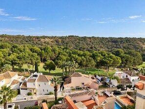 A residential area with houses, a golf course, and a forested hill in the background. - New listing! Stunning penthouse with views, large terraces, close to everything (VC)