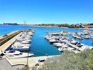A marina with numerous boats docked, a clear sky, and a cityscape in the background. - New listing! Stunning penthouse with views, large terraces, close to everything (VC)