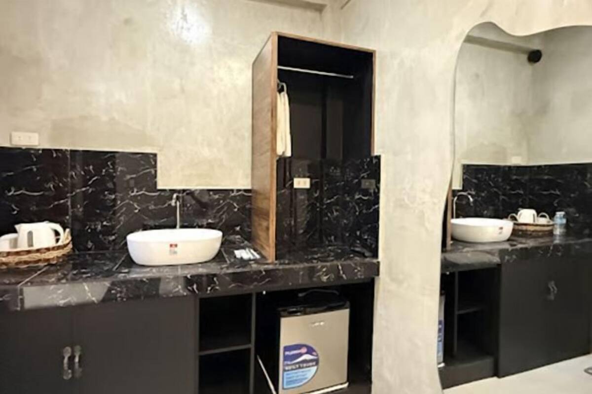 Een moderne badkamer met een marmeren aanrecht, een witte wastafel en een houten kastje.