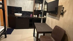 A bathroom with a sink, mirror, and a flat-screen TV mounted on the wall. - HM Eco Hotel Naia (Pasay)