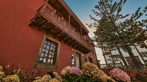 A traditional building with a wooden balcony, large windows, and a red facade. - The Attic (Moya)