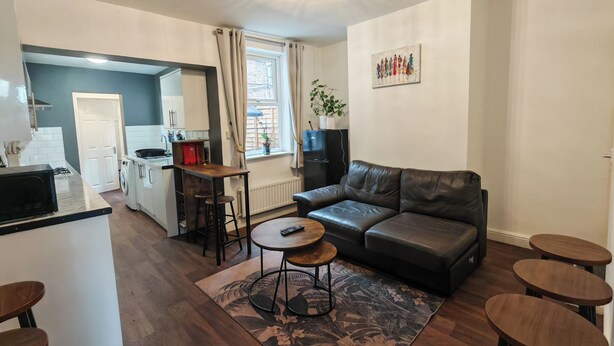 Un salon moderne avec un canapé en cuir, une table basse et un coin repas équipé de tabourets.