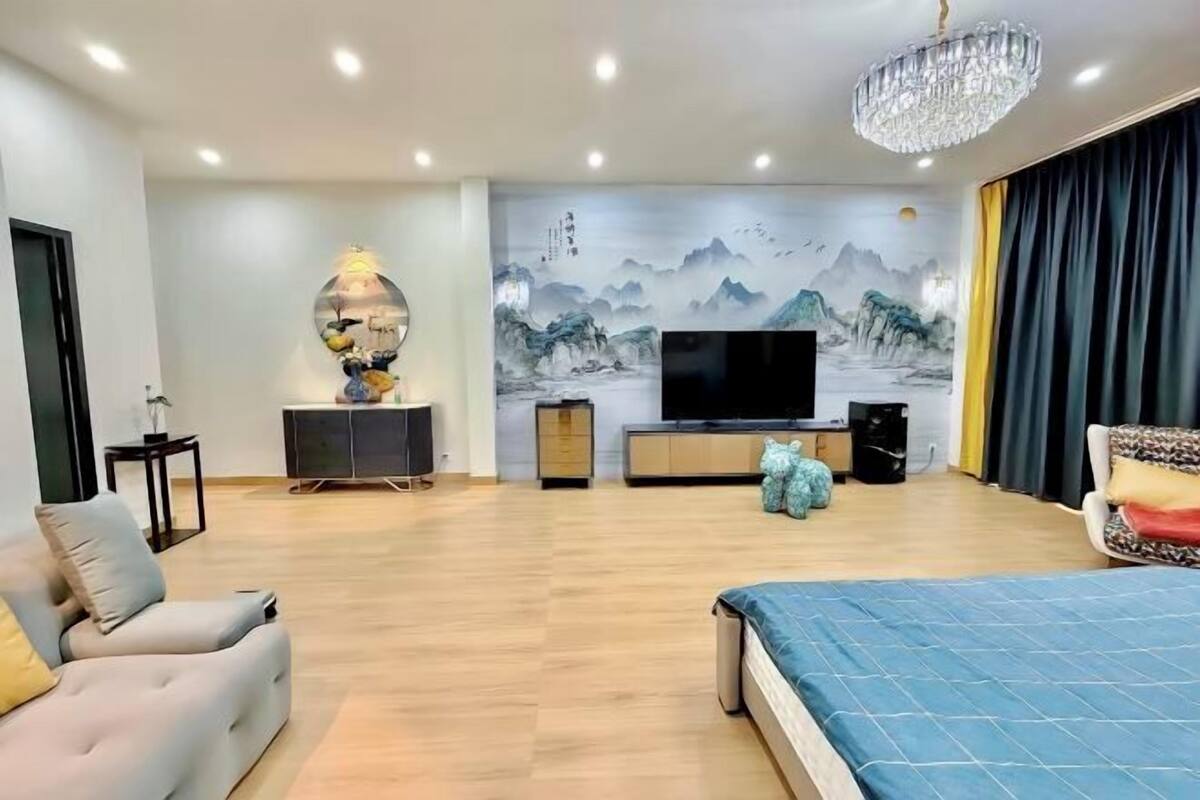 Un salon moderne doté d’un grand téléviseur à écran plat, d’un lustre et d’une fresque murale.
