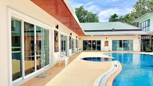 A modern house with a swimming pool, large glass doors, and a covered patio area. - Chuan Pool Villa Rawai Phuket (Phuket)
