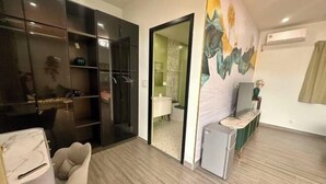 A modern living room with a sofa, a small table, a TV, a wardrobe, and a bathroom visible through an open door. - Chuan Pool Villa Rawai Phuket (Phuket)