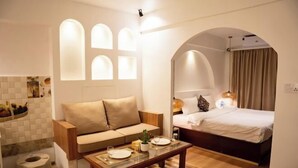 A modern hotel room with a sofa, a bed, a dining table, and a small kitchen area. - Nagpukhu Guest House (Bhaktapur)