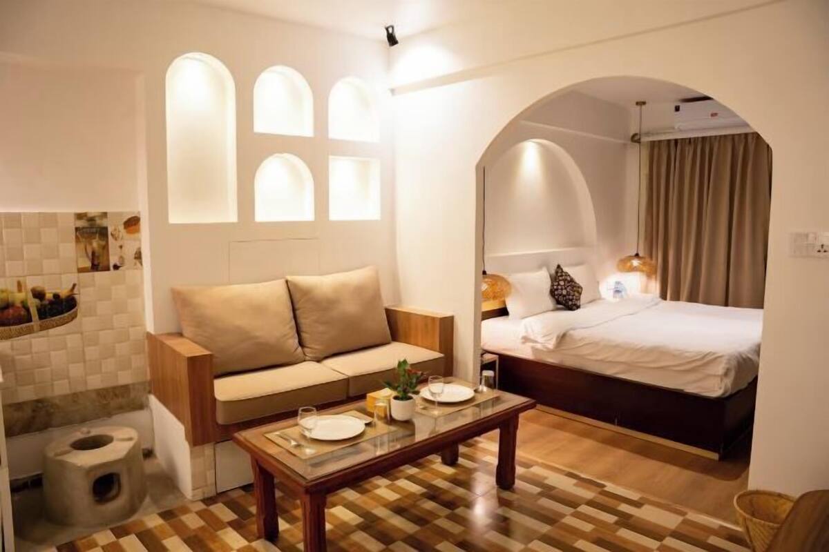 Una camera d'albergo moderna con un divano, un letto, un tavolo da pranzo e un angolo cottura.