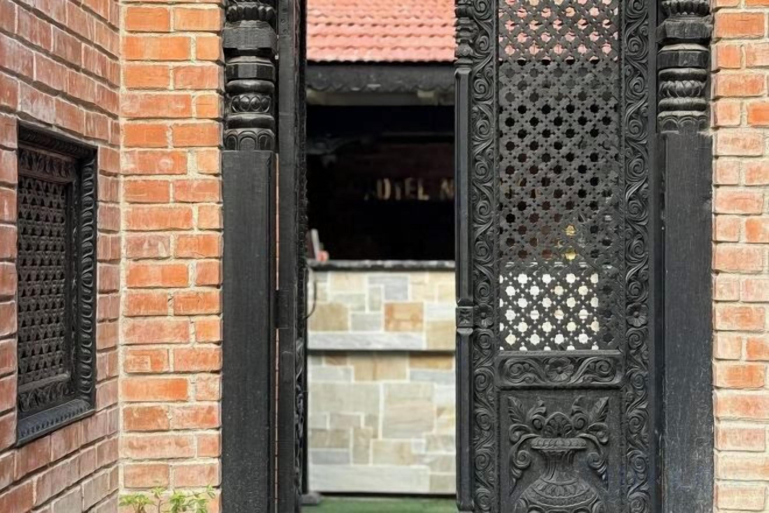 A doorway with intricate metalwork and a brick wall.