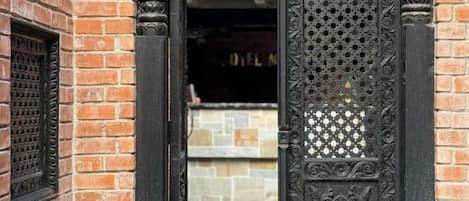 A doorway with intricate metalwork and a brick wall.