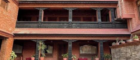 A multi-story building with a courtyard, featuring a traditional architectural style with balconies and columns.