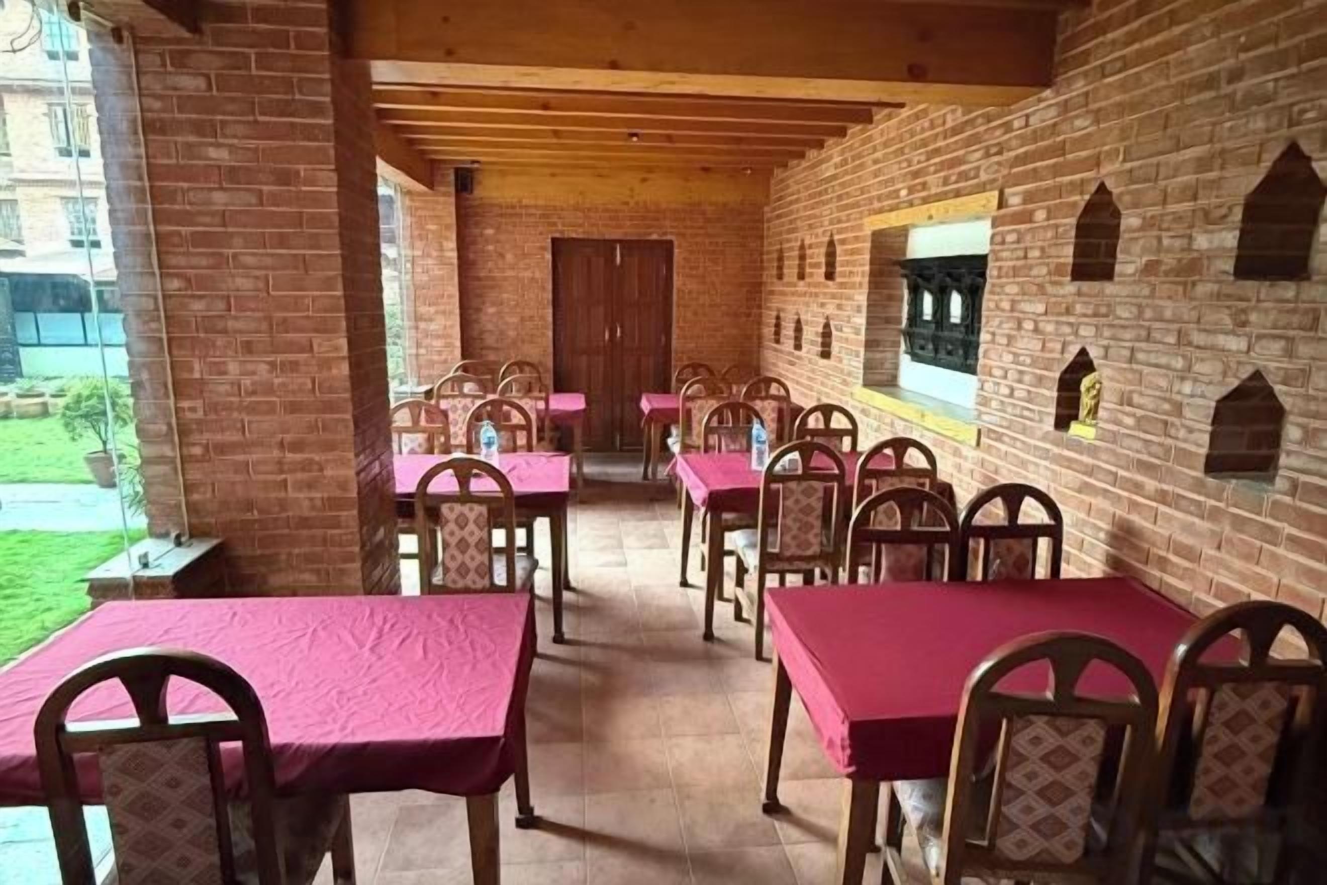 A covered outdoor dining area with brick walls, wooden tables, and chairs.