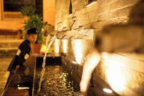 A water feature with a stone wall and a child playing nearby. - Nagpukhu Guest House (Bhaktapur)
