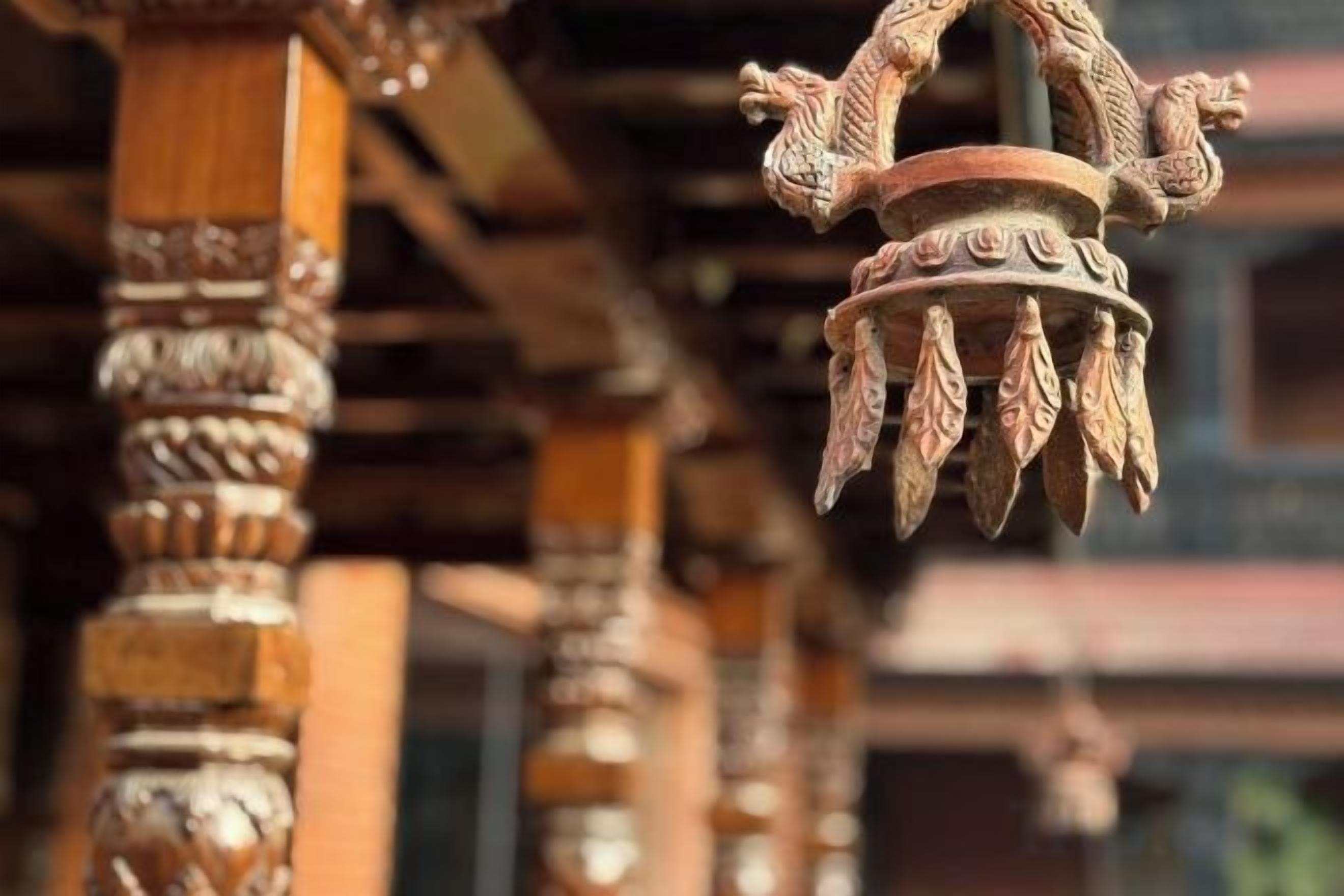 Primer plano de una estructura de madera con detalles tallados y un adorno colgante.