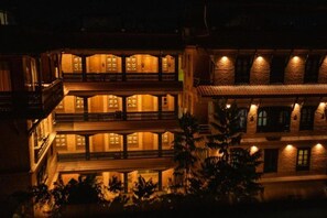 Een meerlaags gebouw met balkons en warme verlichting.