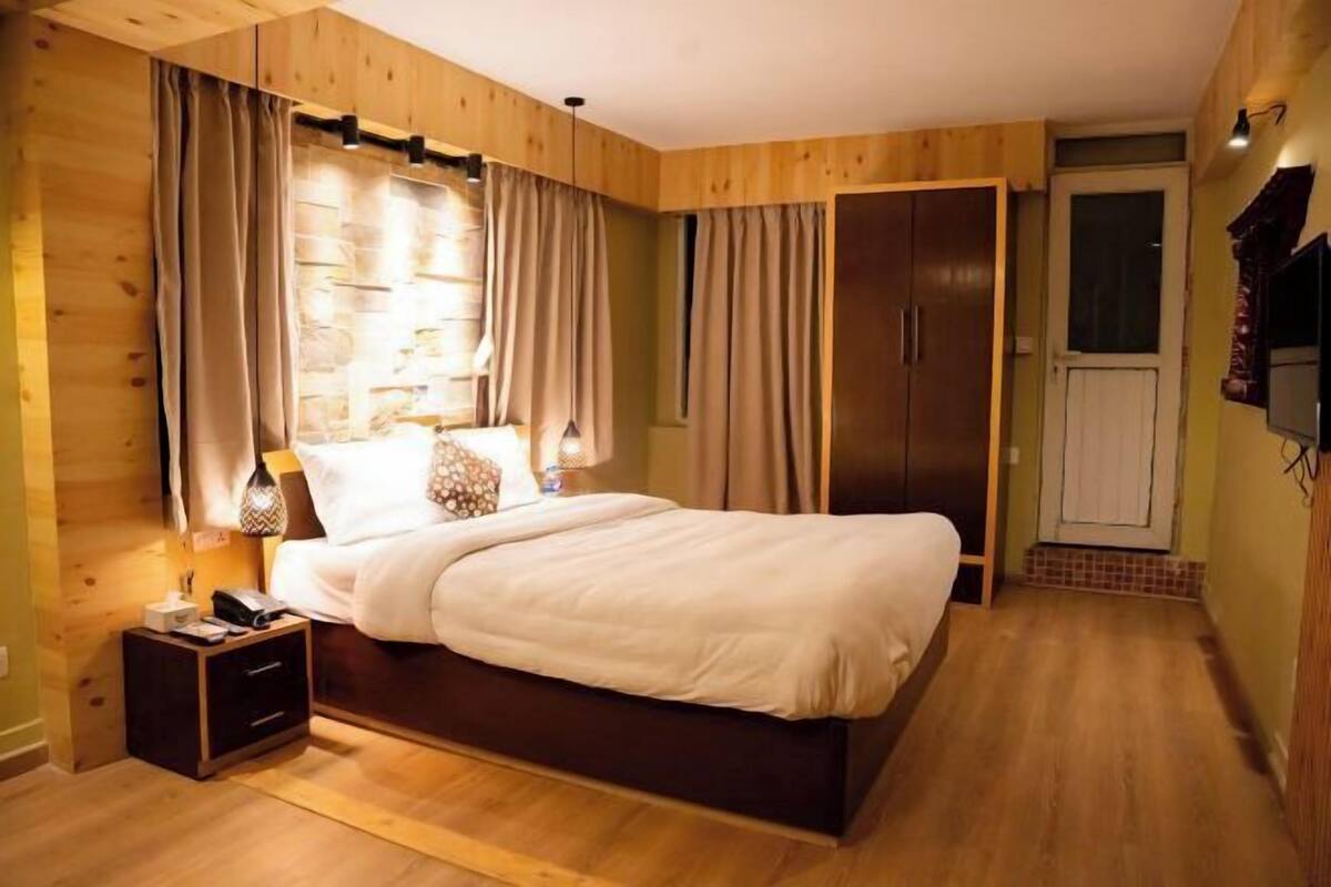Camera da letto con testiera in legno, comodino con lampada, armadio e una porta.