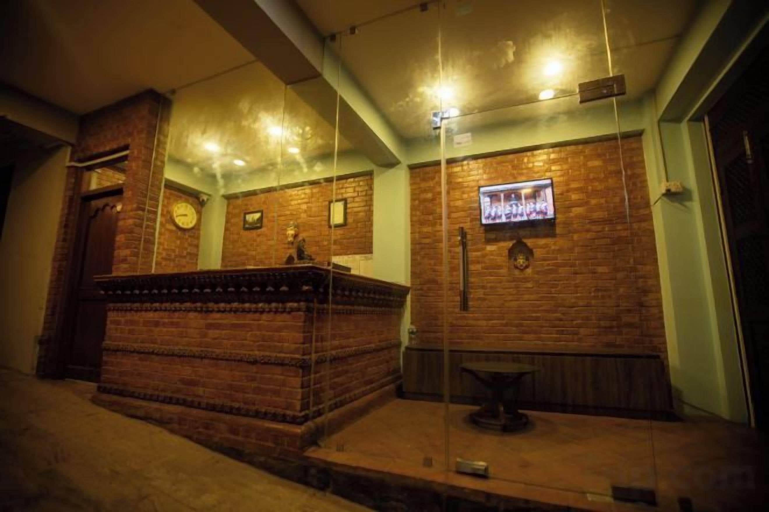 A lobby with a reception desk, a clock, and a television screen.
