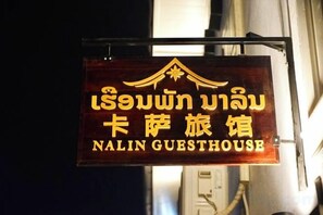 Een bord met tekst in twee talen, dat een pension 'NALIN GUESTHOUSE' aangeeft.