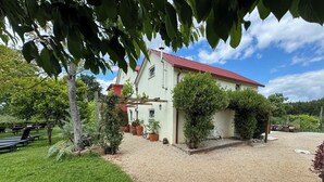 A house with a red roof, a gravel driveway, and a garden with potted plants and a bicycle. - Agroturismo Quinta Vale Salgueiro - Aurora family house - Serra da Estrela (Carragozela)