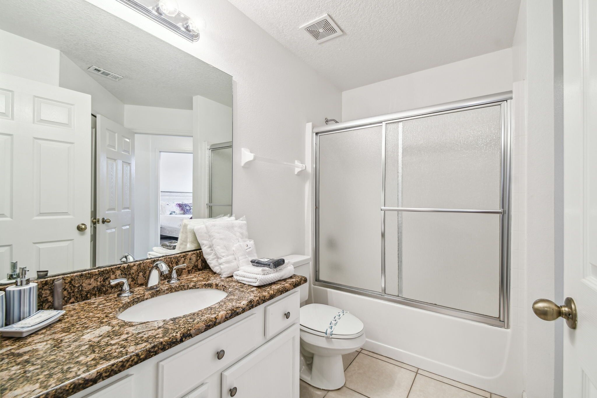A bathroom with a double sink, a large mirror, a shower, and a toilet.