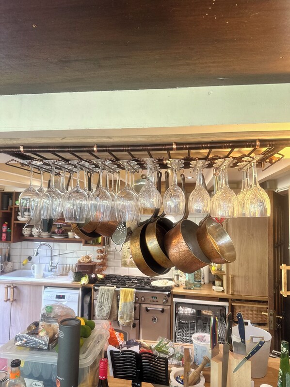 A kitchen with hanging wine glasses, pots, and a variety of kitchen utensils.