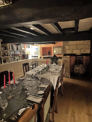 A dining room with a long table set for a meal, bookshelves, and a fireplace.