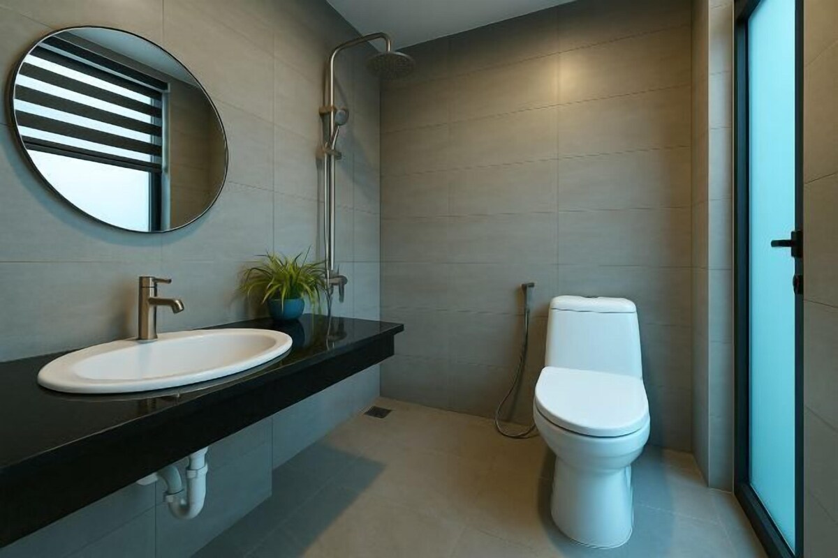 Un baño moderno con un espejo redondo, un lavabo, un inodoro y una ducha.
