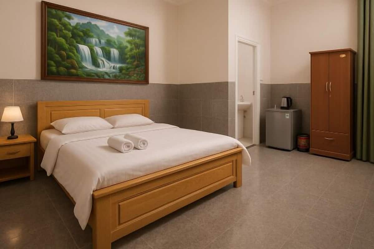 Une chambre d’hôtel comprenant un lit, une table de chevet, un tableau, une armoire et une machine à café.