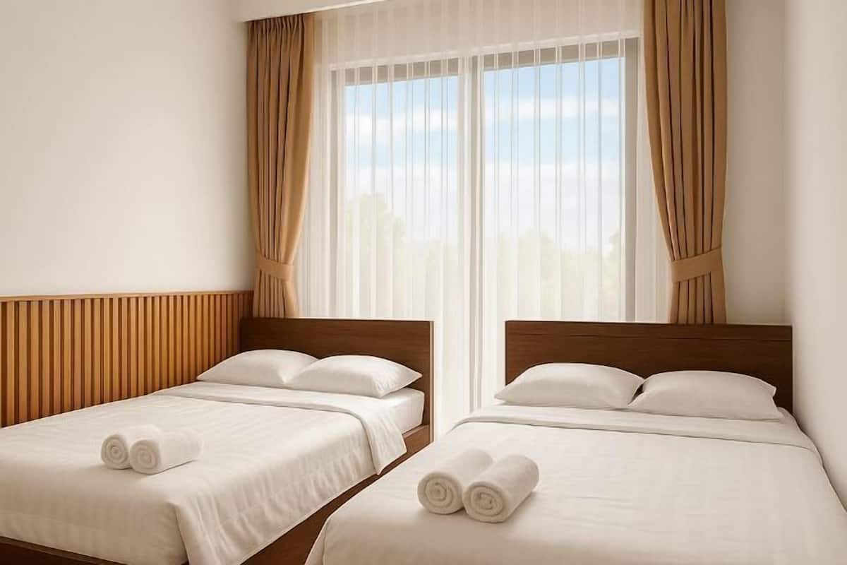 Une chambre d’hôtel avec deux lits simples, une tête de lit en bois, du linge de lit blanc et une grande fenêtre avec des rideaux.