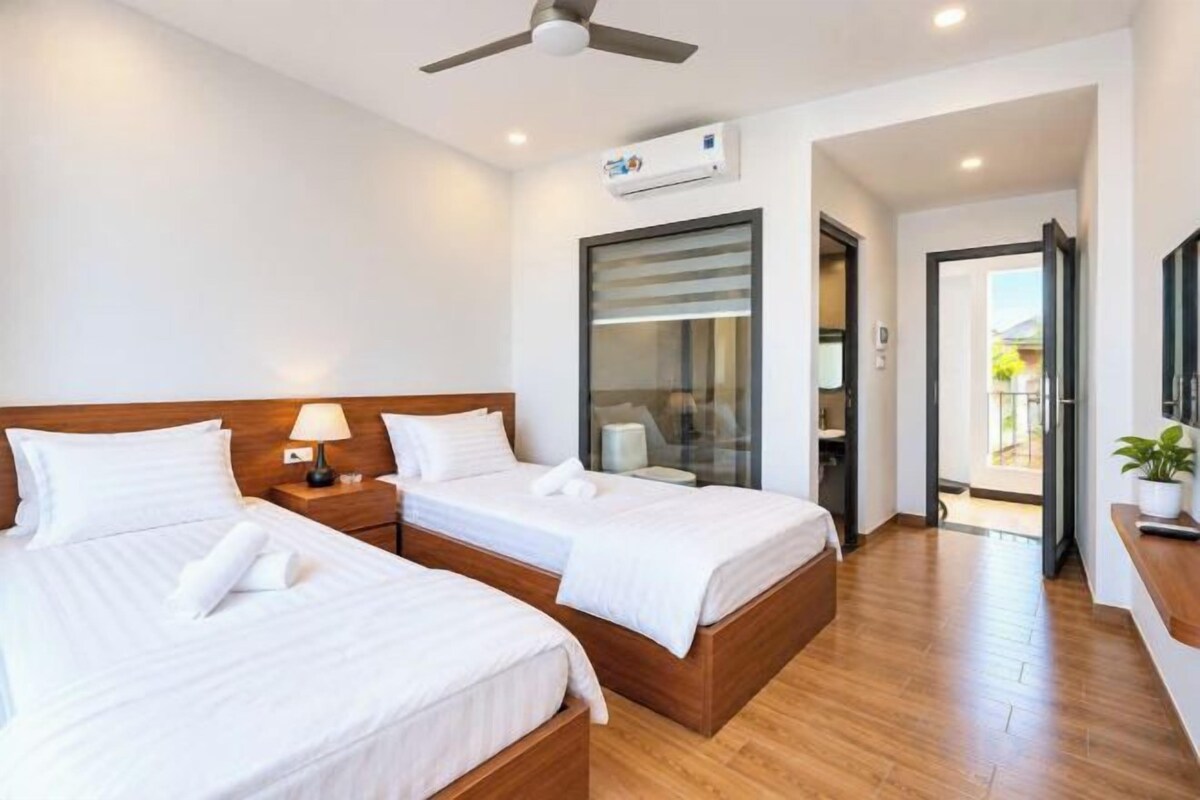 A hotel room with two beds, a ceiling fan, an air conditioning unit, and a view of the outside.