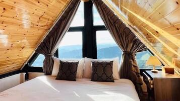 Un dormitorio con una cama grande, cortinas, un escritorio y vistas al exterior.
