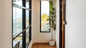 A narrow hallway with a large window, a potted plant, and a door with a mounted animal head. - Sinsup villa private Mountain View (Mae Suai)