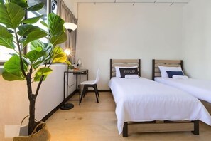 A hotel room with two beds, a desk, a chair, a potted plant, and a window. - 7-Room Exec House, Rumahku Express, Georgetown (George Town)